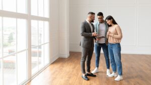 Couple Buying New Apartment, House Agent Showing Tablet