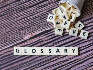 Glossary word made from square letter tiles on wooden background.